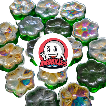 Vue rapprochée de plusieurs billes plate Fleur Cosmos vertes et irisées, en verre, disposées autour du logo MesBilles.
